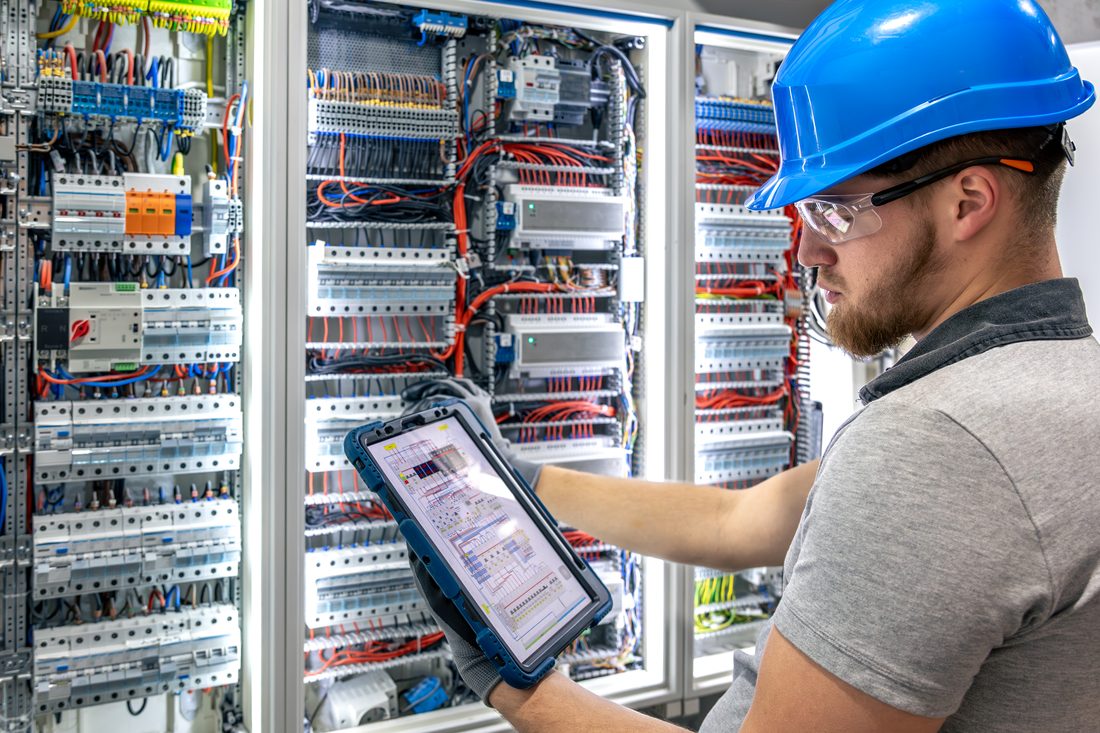 Engineer checking control panel wiring with a tablet